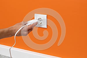 Man plugging phone adapter into a electrical outlet