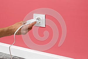 Man plugging phone adapter into a electrical outlet