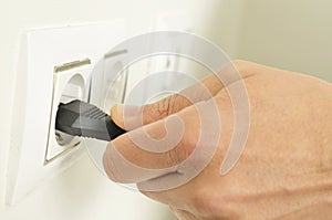 Man plugging in or unplugging an electrical plug in a socket