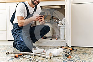 Man plumber work in uniform indoors using mobile phone