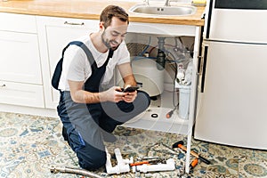 Man plumber work in uniform indoors using mobile phone