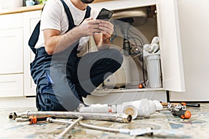 Man plumber work in uniform indoors using mobile phone