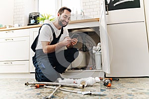 Man plumber work in uniform indoors using mobile phone