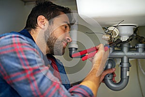 Man, plumber and wrench with pipe for repair, service or fix in home maintenance or indoor leak. Young male person