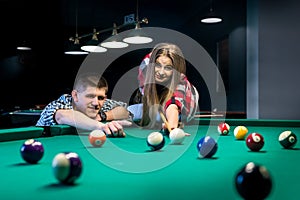 Man pointing ball for shoot, couple playing billiard.