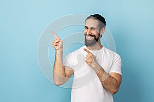 Man pointing finger aside, showing copy space for commercial text, blank wall with idea presentation