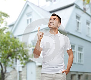 Man pointing finger up over house background