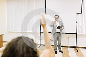 Man pointing at the girl on a classroom background. Student raising hand for an answer. Education concept.