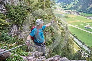 Man pointing his hand towards Zillertal valley, Austria, from high on a via ferrata route called Pfeilspitzwand, near Mayrhofen