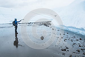 Man pointing with an ice axe at a steep ice wall in front of him