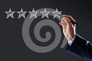 Man pointing at icons of five stars on dark grey background, closeup. Quality rating