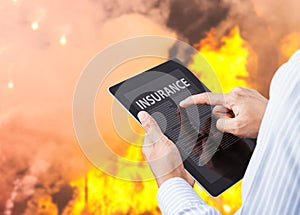 Man pointing at insurance wording on tablet with fire