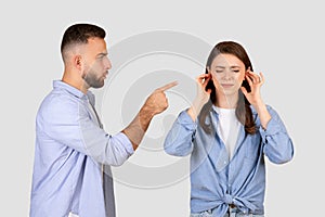 Man pointing at lady angrily, woman blocking ears