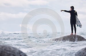 Man, pointing or surfer on rocks at beach, ocean or rough sea and watching tide, waves or water movement in Hawaii