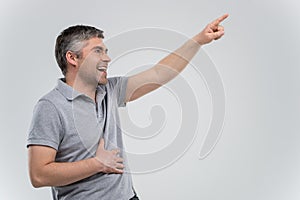 Man pointing up and laughing on grey background.