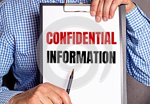 The man points with a pen to the text CONFIDENTIAL INFORMATION on a white sheet