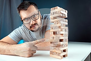 The man points to the Column of the game of jenga. The concept of a mortgage, investment risks, economic crisis, economic