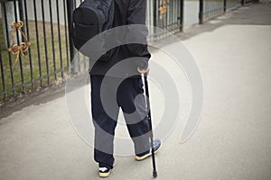 A man with a pole when walking. A pensioner in Russia walks down the street