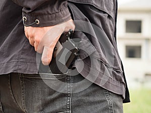 A man, policeman or robber, gangster concealing his gun behind his back
