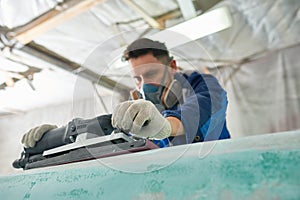 Man Polishing Boats in Workshop