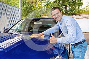 Man polishing car on a car wash. The man holds the microfiber in hand and polishes the car