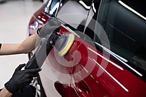 Man polishing car paint varnish in detailing studio photo