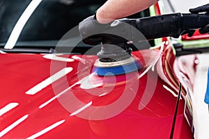 Man polishing car varnish with hand electric polisher.