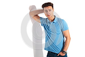 Man in polo shirt leaning his elbow on wall