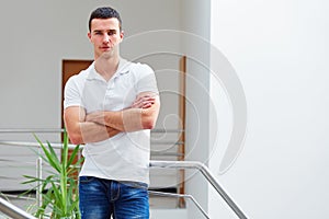 Man in a polo shirt stands leaning on railing