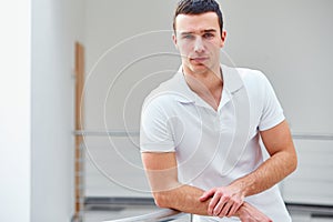 Man in a polo shirt stands leaning on railing