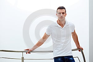 Man in a polo shirt stands leaning on railing photo
