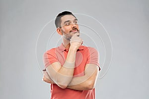 Man in polo t-shirt thinking over gray background