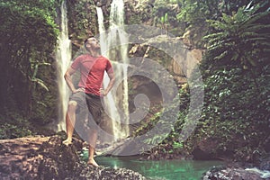 Man in pool at the base of large waterfall