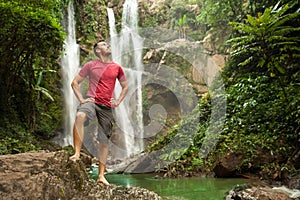 Man in pool at the base of large waterfall