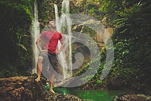 Man in pool at the base of large waterfall