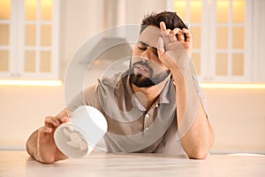 Man with portable fan suffering from heat at home. Summer season