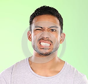 Man, portrait and angry face with disgust for awkward humor or funny humor on a green studio background. Frustrated male