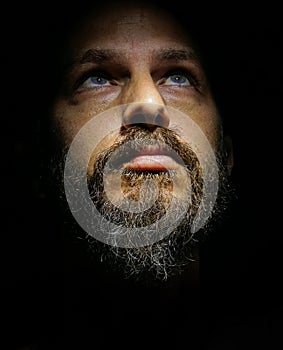 Man portrait. Close up. Face man portrait. lowkey black background. blue eyes. israeli model. beard mustach. serious