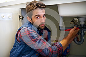 Man, portrait and plumbing with wrench for pipe repair, service or fix in home maintenance or indoor leak. Male person