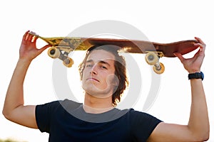 Man, portrait and skateboard on head outdoor for hobby, skill practice and cruising. Male person, relax or rest in
