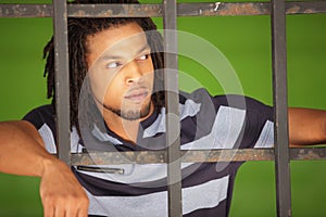 Man posing behind bars