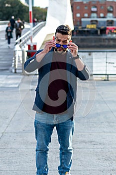 man posing in the city with his blue sunglasses