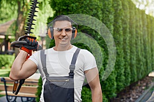 Man posing at garden with electric hedge trimmer in hands