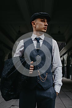 A man posing in the image of an English retro gangster in Peaky blinders style at city street photo