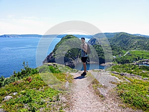 A man posing for a photo with beautiful views hiking the east coast trail off the coast of Newfoundland and Labrador, Canada.
