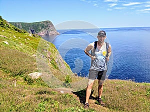 A man posing for a photo with beautiful views hiking the east coast trail off the coast of Newfoundland and Labrador, Canada.