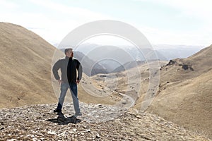 Man posing on rocky ridge of Caucasus background
