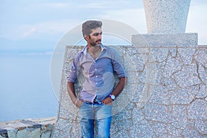 Man posing while standing near a concrete wall bridge above the sea