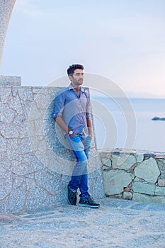 Man posing while standing near a concrete wall bridge above the sea
