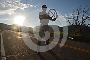 Man posing with steering wheel on mountain road